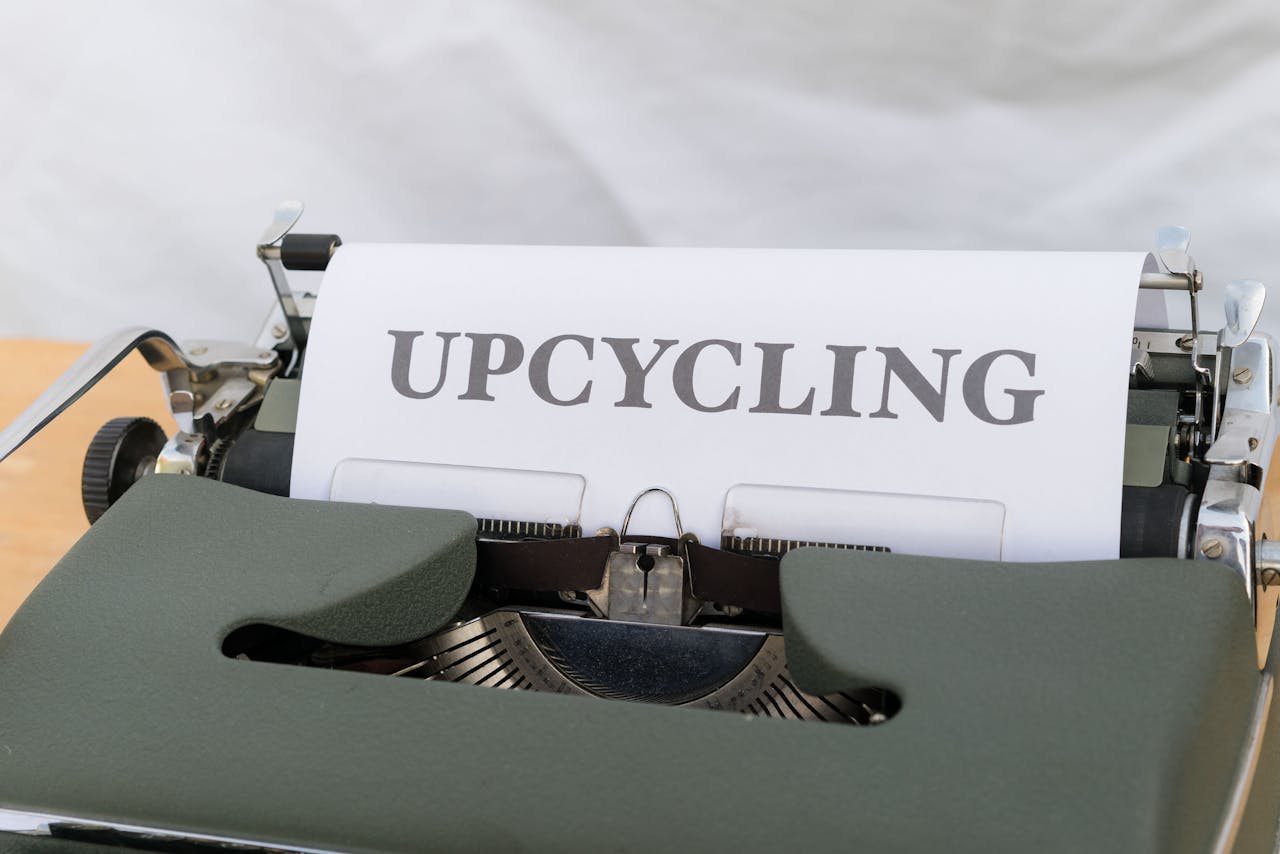 A close-up of a vintage typewriter displaying the word UPCYCLING on its paper.
